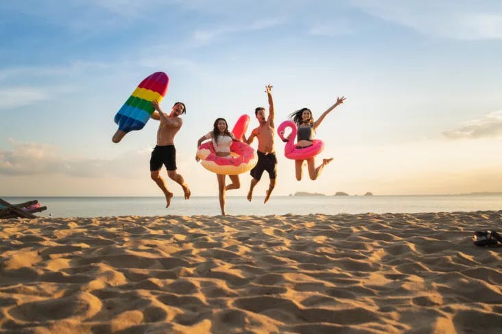 Springende glückliche Freunde im Urlaub am Meer