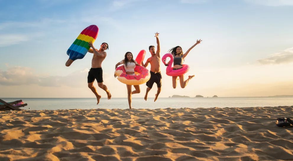 Springende glückliche Freunde im Urlaub am Meer